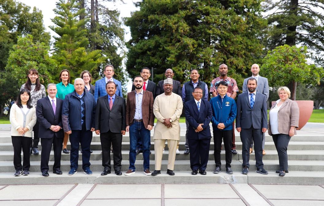 group of men and women standing in front of beautiful green trees